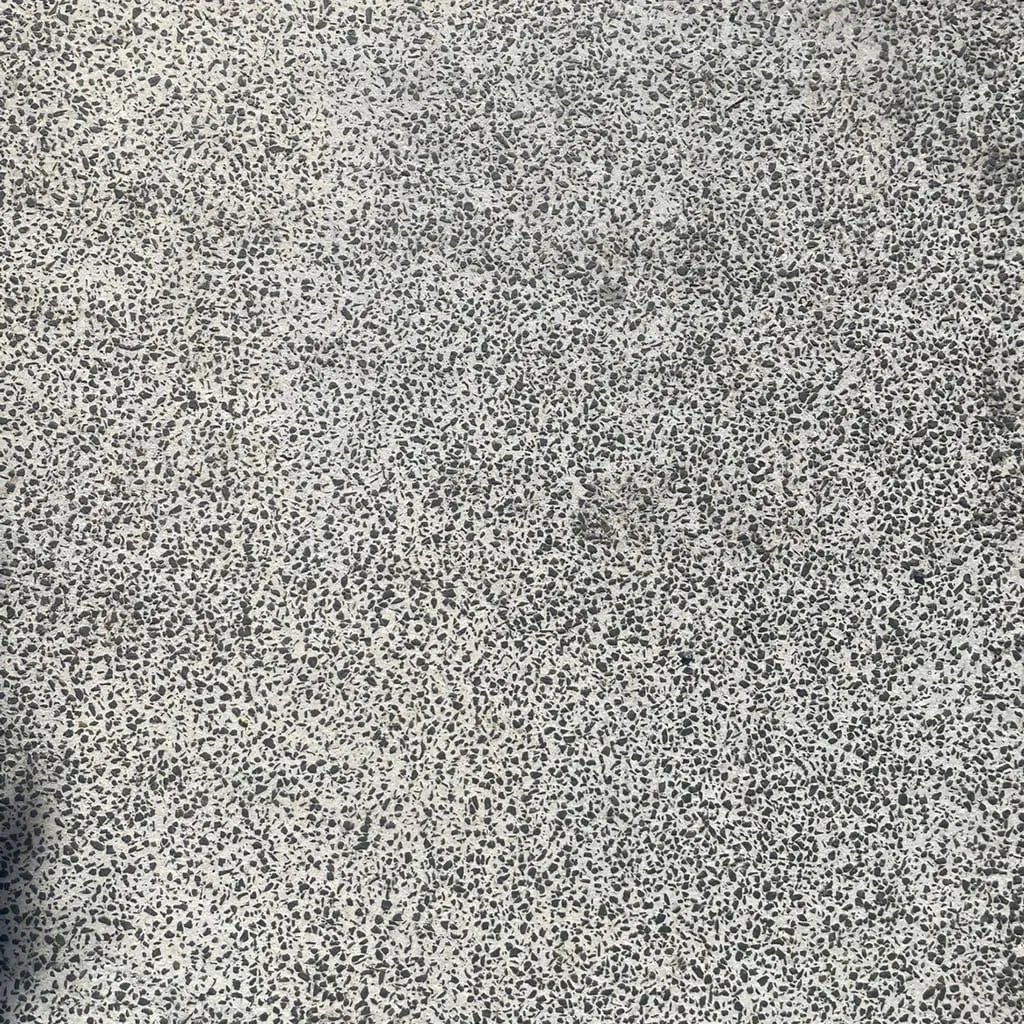 Close-up of a real exposed-aggregate concrete surface, the texture used to build the site's interactive WebGL hero.